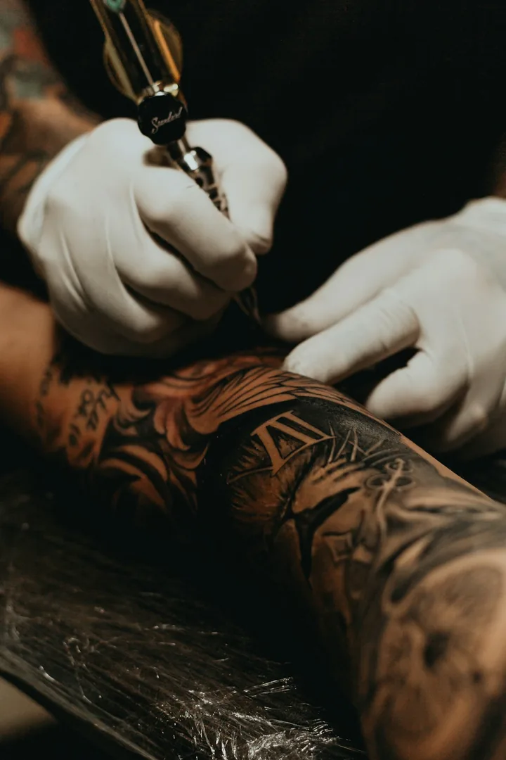 Tattoo artist lining work on a client's arm